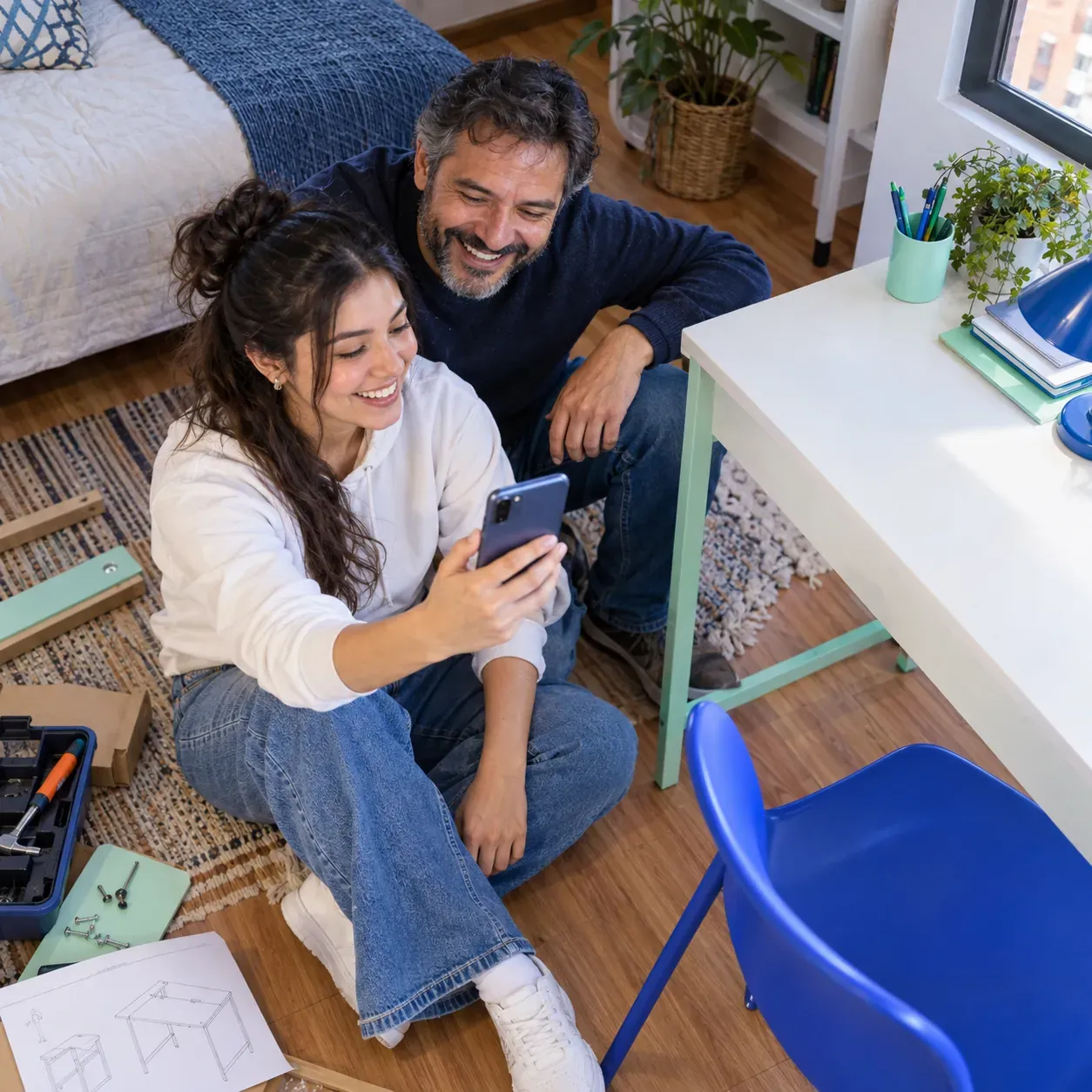 Padre e hija sentados juntos mirando la pantalla de un celular